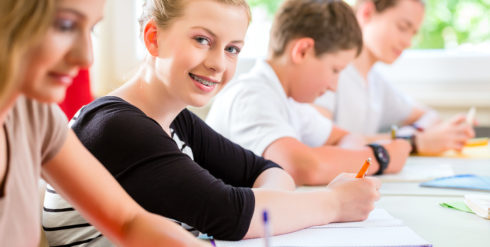 Students or pupils of school class writing an exam test in classroom concentrating on their work